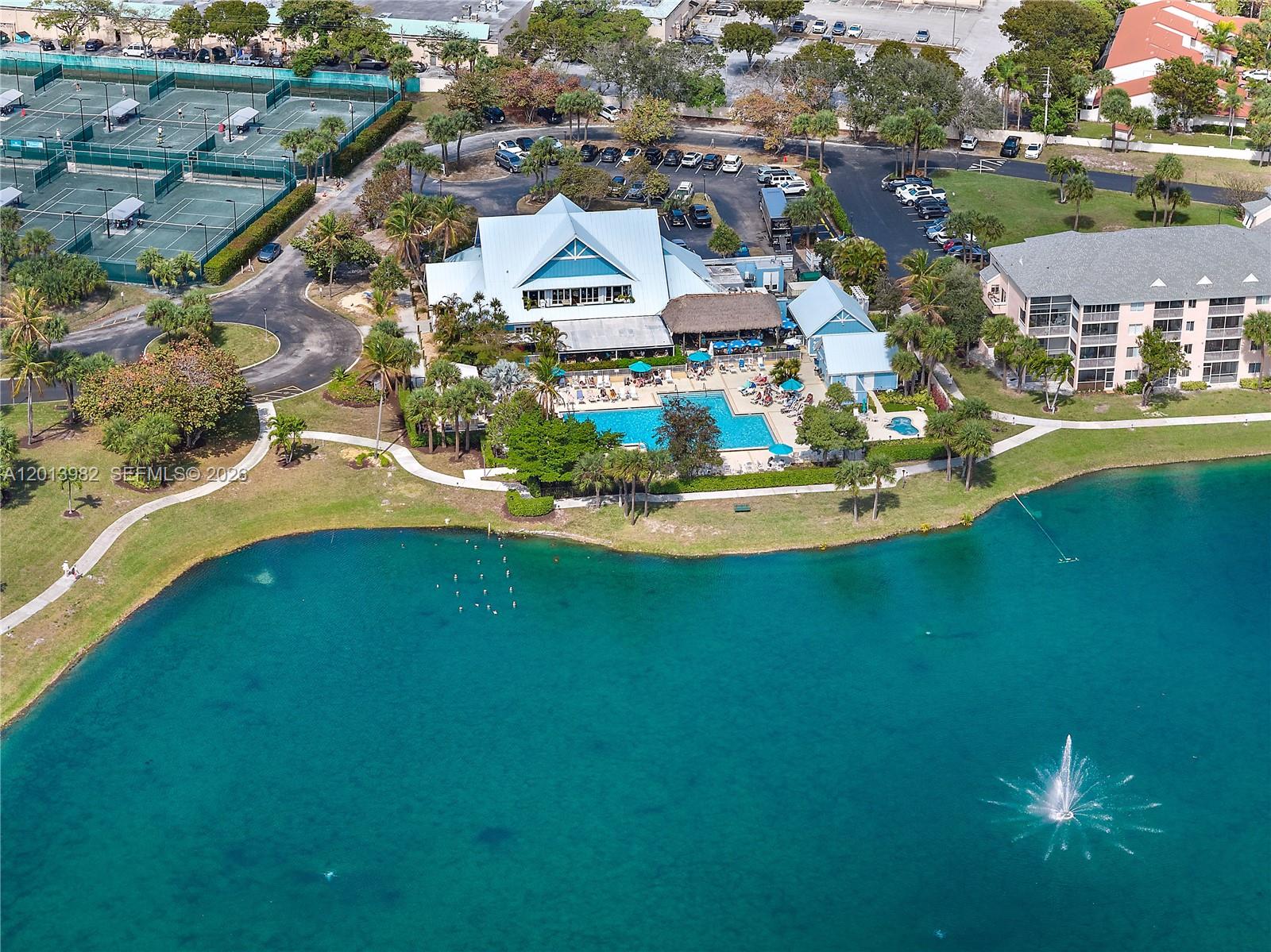 An aerial view shows a clubhouse with a pool, tennis courts, and a lake — 275 Palm Ave # A205, Jupiter FL 33477, JUPITER, FL