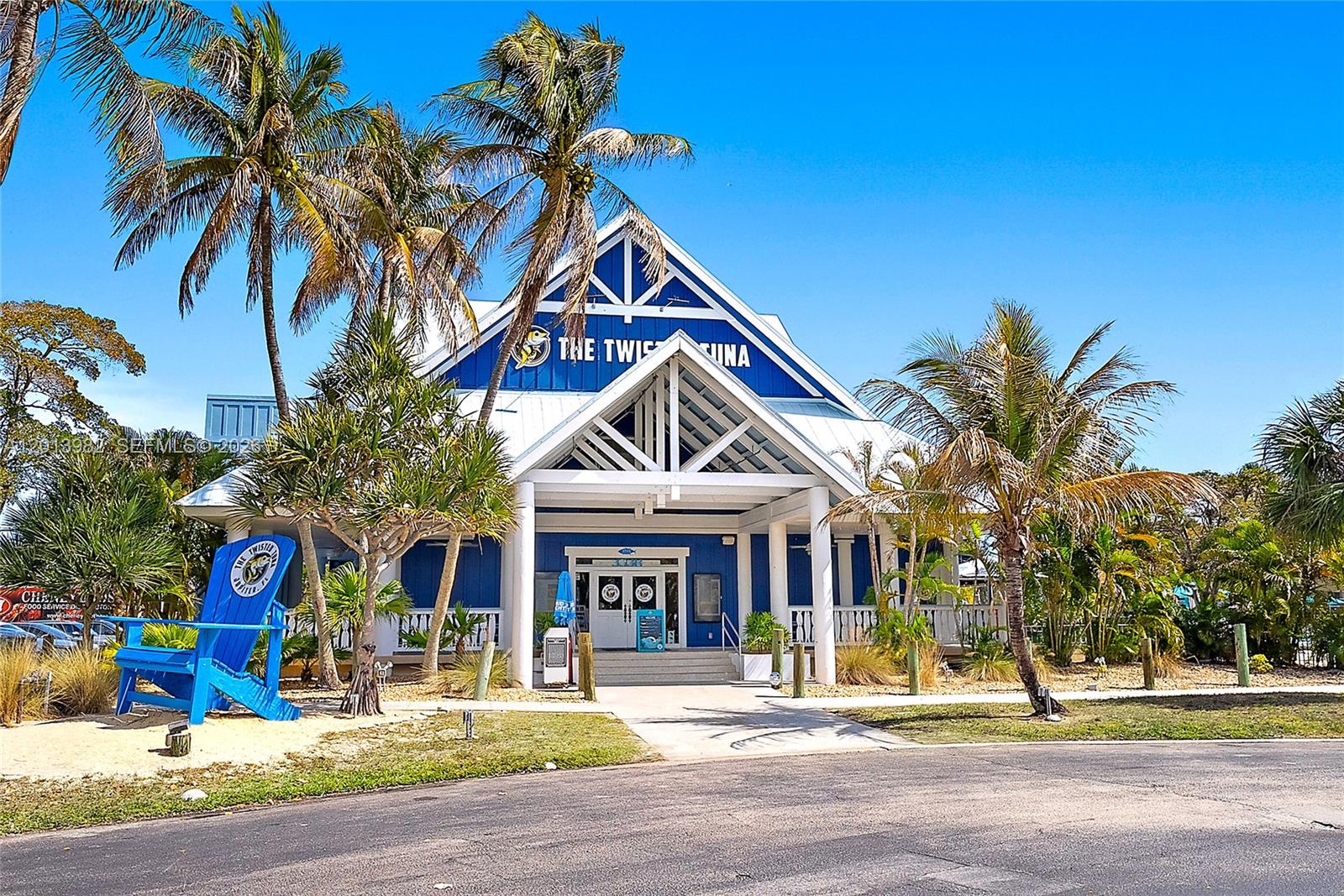 A blue and white building with a large wooden chair sits under palm trees — 275 Palm Ave # A205, Jupiter FL 33477, JUPITER, FL