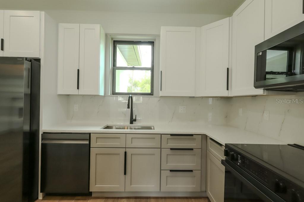 A kitchen with white upper cabinets, light gray lower cabinets, and a white marble backsplash — 5438 SYLVANIA AVENUE, NORTH PORT, FL