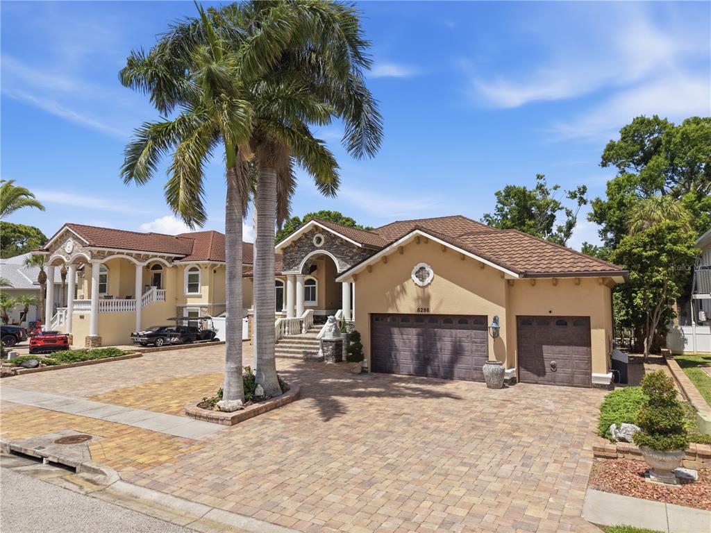 A tan stucco house with a tiled roof and a paved driveway featuring palm trees — 8286 N 97TH N ST, SEMINOLE, FL