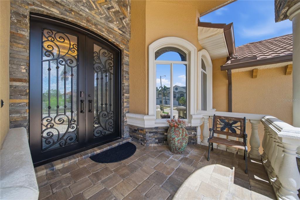 An arched double door with iron scrollwork opens onto a stone-paved entryway porch — 8286 N 97TH N ST, SEMINOLE, FL