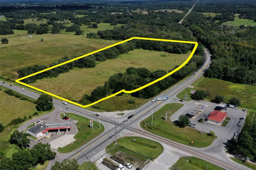 An aerial view shows a vacant, grassy lot outlined in yellow at a road intersection — 3070 SR-50, WEBSTER, FL