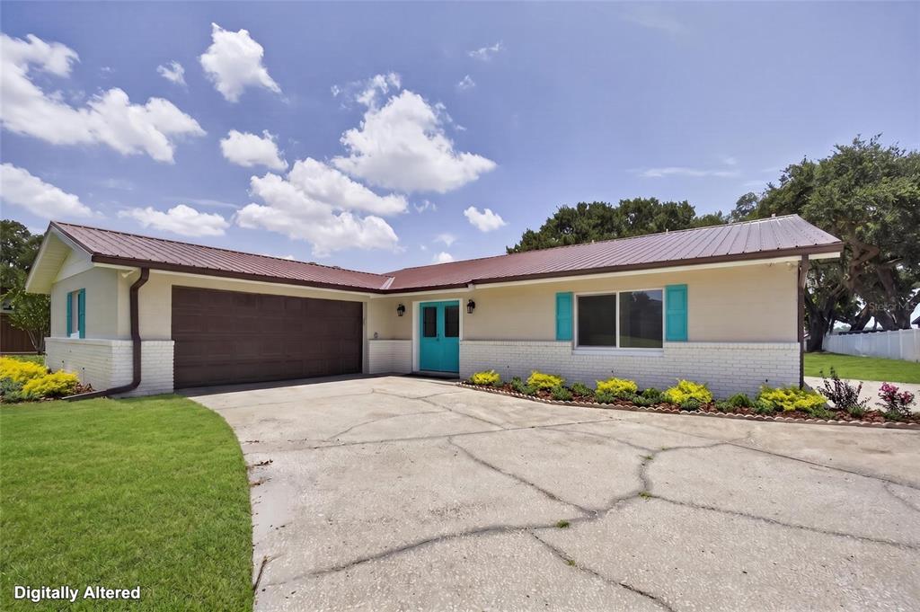 A single-story house with a brown metal roof, white brick base, and teal accents — 1225 HOFFNER AVENUE, ORLANDO, FL