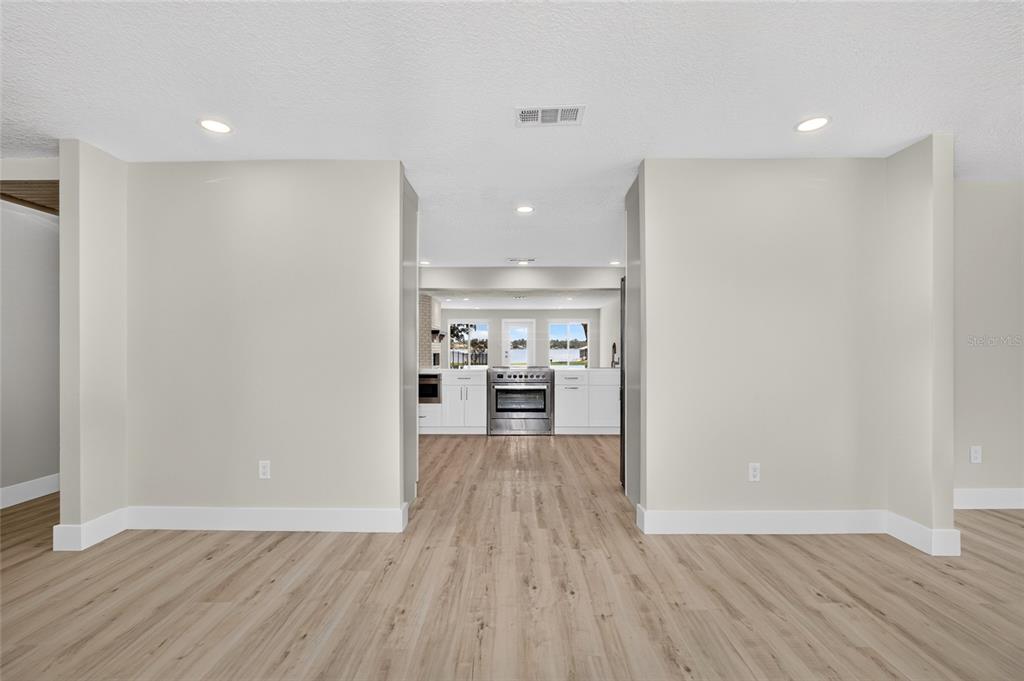 A view through a wide doorway into a bright kitchen with white cabinets and appliances — 1225 HOFFNER AVENUE, ORLANDO, FL