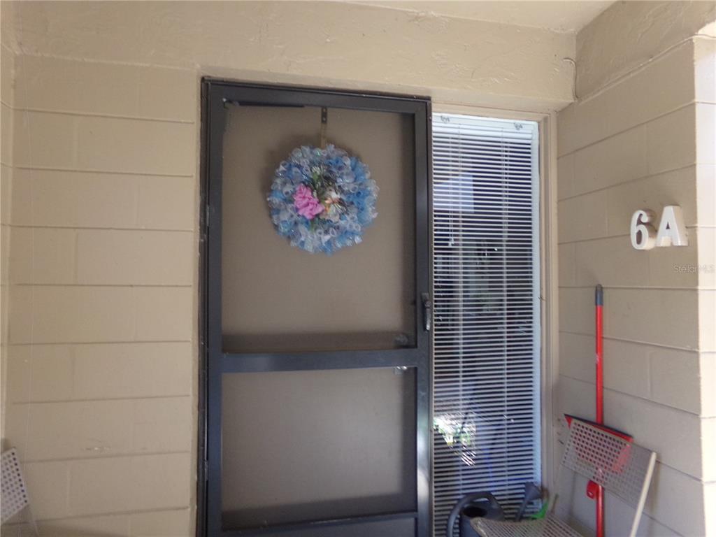 A residential entryway features a dark screen door with a wreath and a side window — 110 CYPRESS WOODS CT UNIT 6A, DELTONA, FL