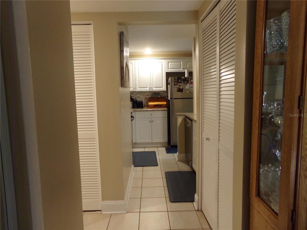 A view through a hallway into a kitchen with white cabinets and tiled floors — 110 CYPRESS WOODS CT UNIT 6A, DELTONA, FL