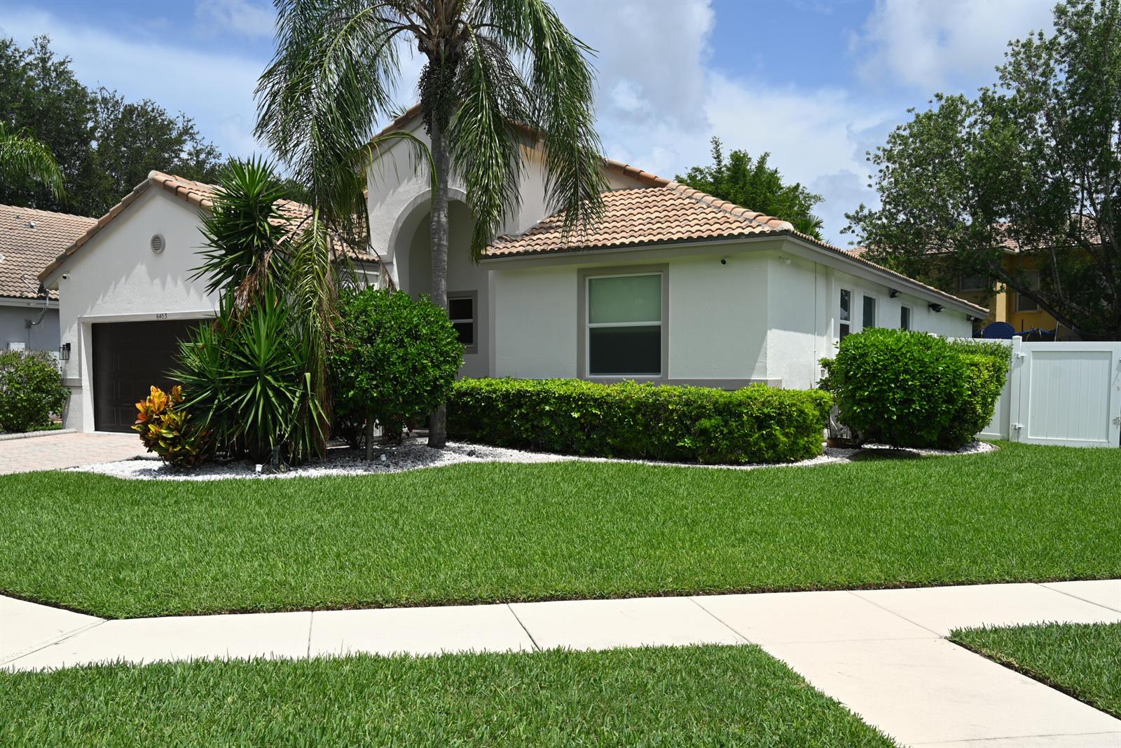 A single-story house with a tile roof, palm tree, and manicured landscaping under a blue sky — 6403 C Durham Drive, Lake Worth FL 33467, LAKE WORTH, FL