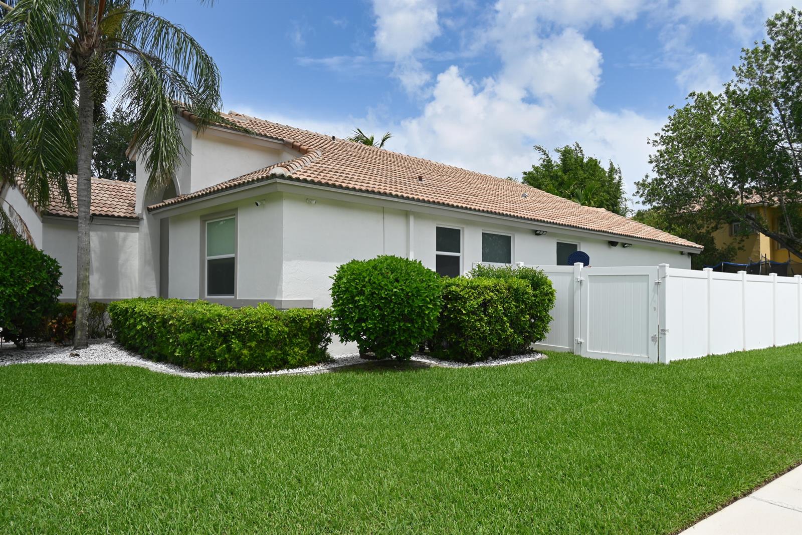 A white house with a tile roof, green hedges, and a white vinyl privacy fence — 6403 C Durham Drive, Lake Worth FL 33467, LAKE WORTH, FL