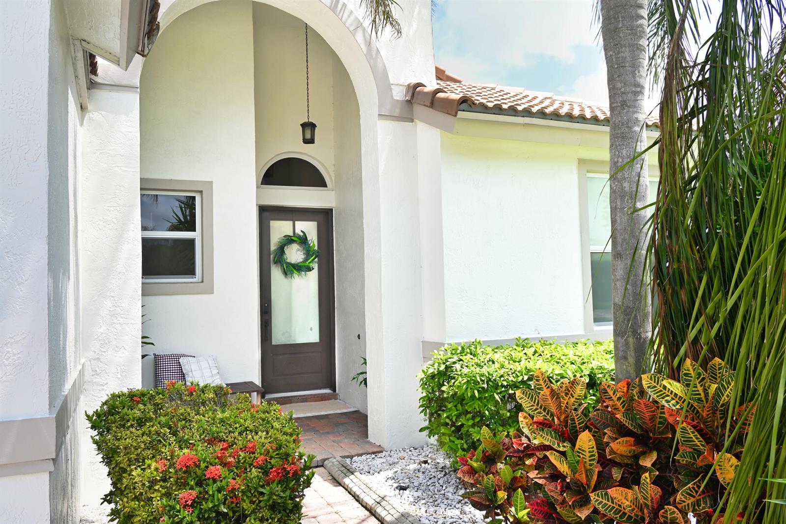 The exterior of a white stucco house features an arched entryway and a dark door — 6403 C Durham Drive, Lake Worth FL 33467, LAKE WORTH, FL