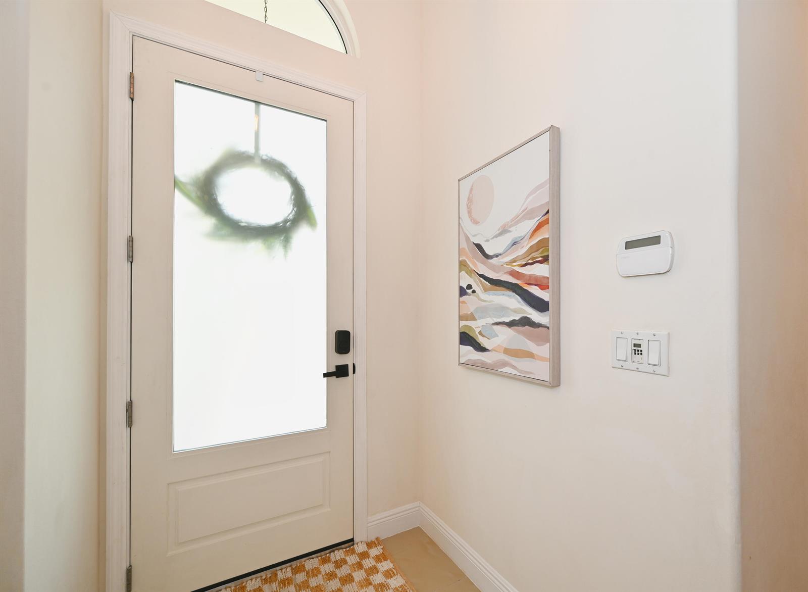 A bright entryway features a white front door with a wreath, wall art, and light flooring — 6403 C Durham Drive, Lake Worth FL 33467, LAKE WORTH, FL