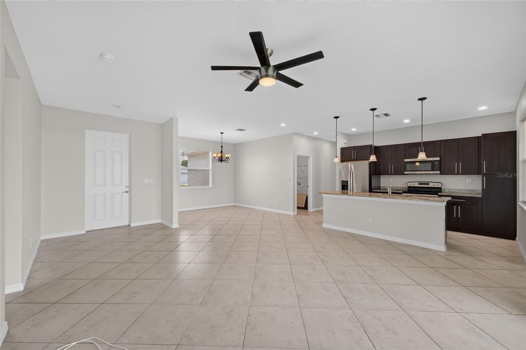 An open-concept kitchen and living area features tile flooring, dark cabinetry, and a ceiling fan — 2714 NW 1ST PLACE, CAPE CORAL, FL