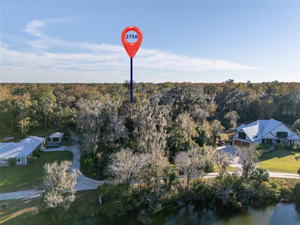An aerial view shows a wooded lot marked with a location pin near a lake — 2750 PEARL LAKE TRAIL, NEW SMYRNA BEACH, FL