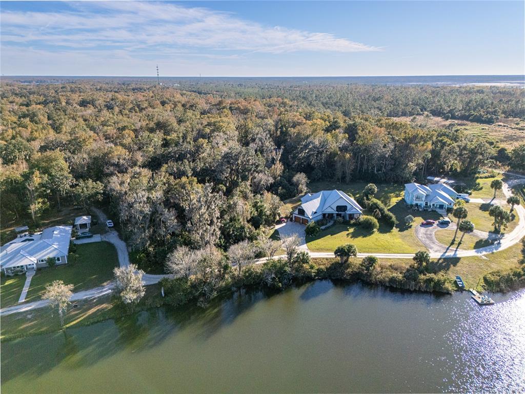 An aerial view shows three houses situated along a lakefront bordered by dense forest — 2750 PEARL LAKE TRAIL, NEW SMYRNA BEACH, FL