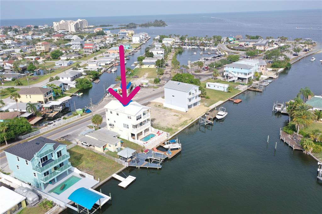 An aerial view shows a multi-story waterfront house with a pool and private dock — 6441 CLARK STREET, HUDSON, FL