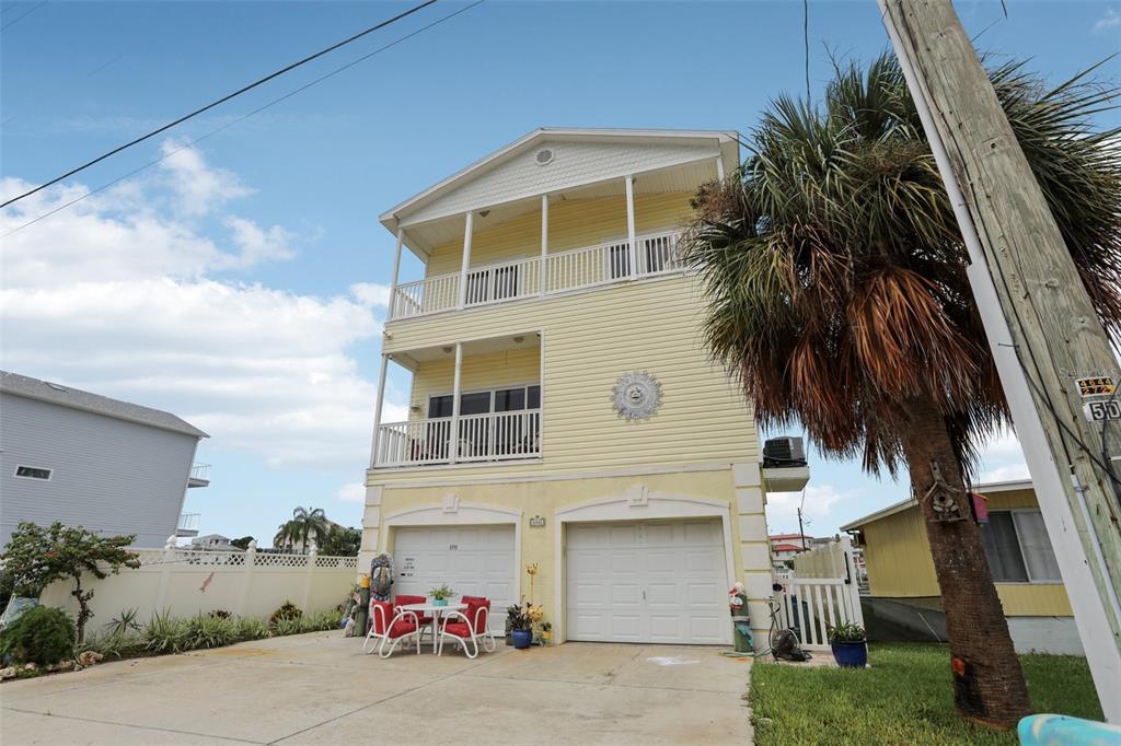 An elevated yellow house features a backyard swimming pool, a patio, and a private boat dock — 6441 CLARK STREET, HUDSON, FL