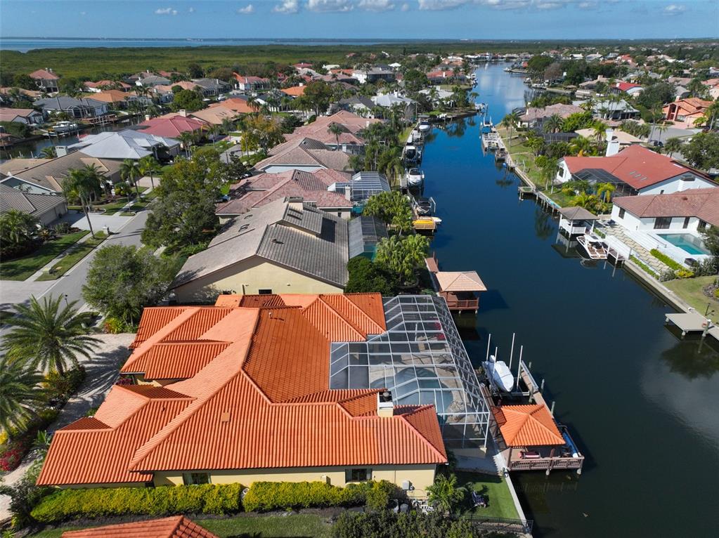 An aerial view shows a waterfront home with a red tile roof and pool enclosure — 9805 COMPASS POINT WAY, TAMPA, FL