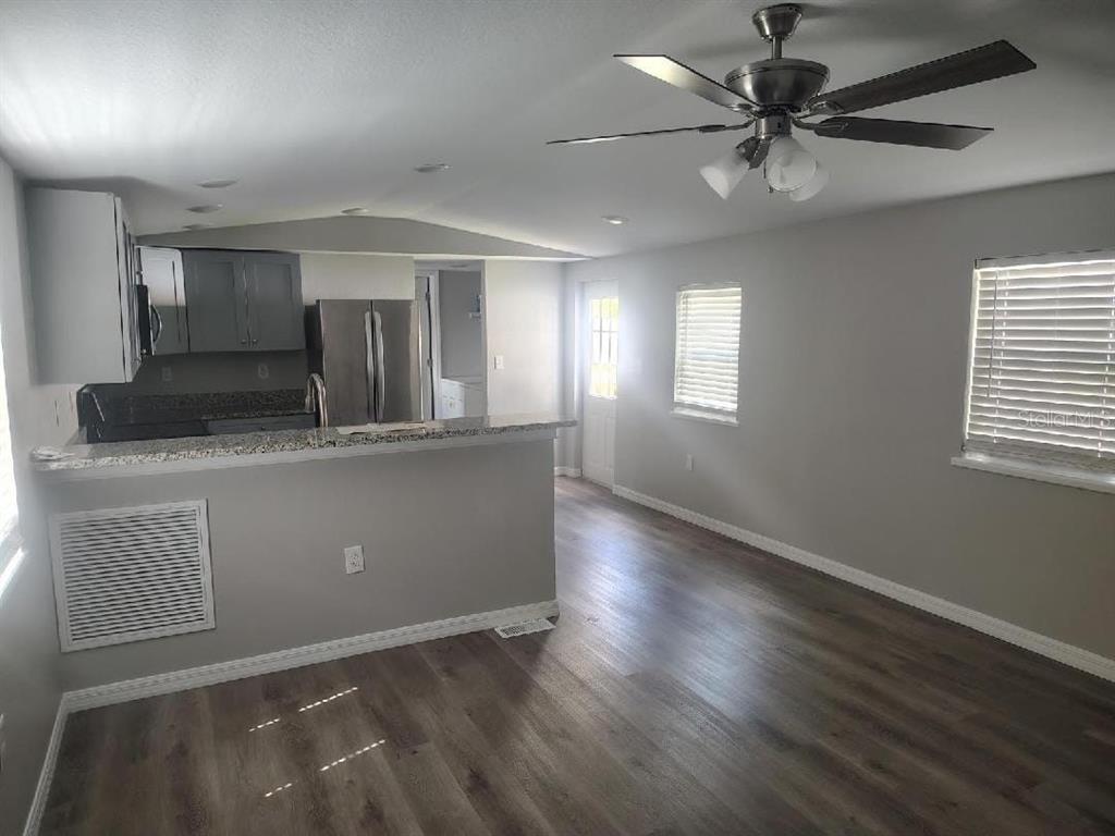 A kitchen with gray cabinets and a granite breakfast bar opens into a living area — 3940 SE 56TH AVENUE, OCALA, FL