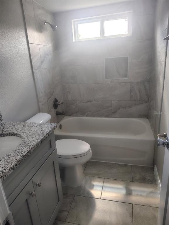 A bathroom features a gray vanity with a granite countertop, a toilet, and a tiled tub-shower — 3940 SE 56TH AVENUE, OCALA, FL