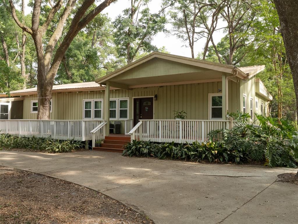 A light green, single-story house with a large wooden deck and a concrete driveway — 5106 SW 177TH STREET, ARCHER, FL