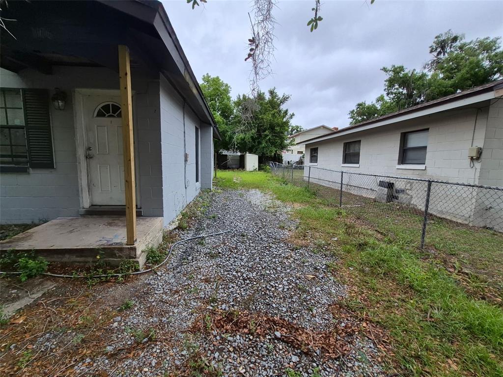 A gravel path runs between two gray concrete block houses separated by a chain-link fence — 1106 SW 5TH STREET, OCALA, FL