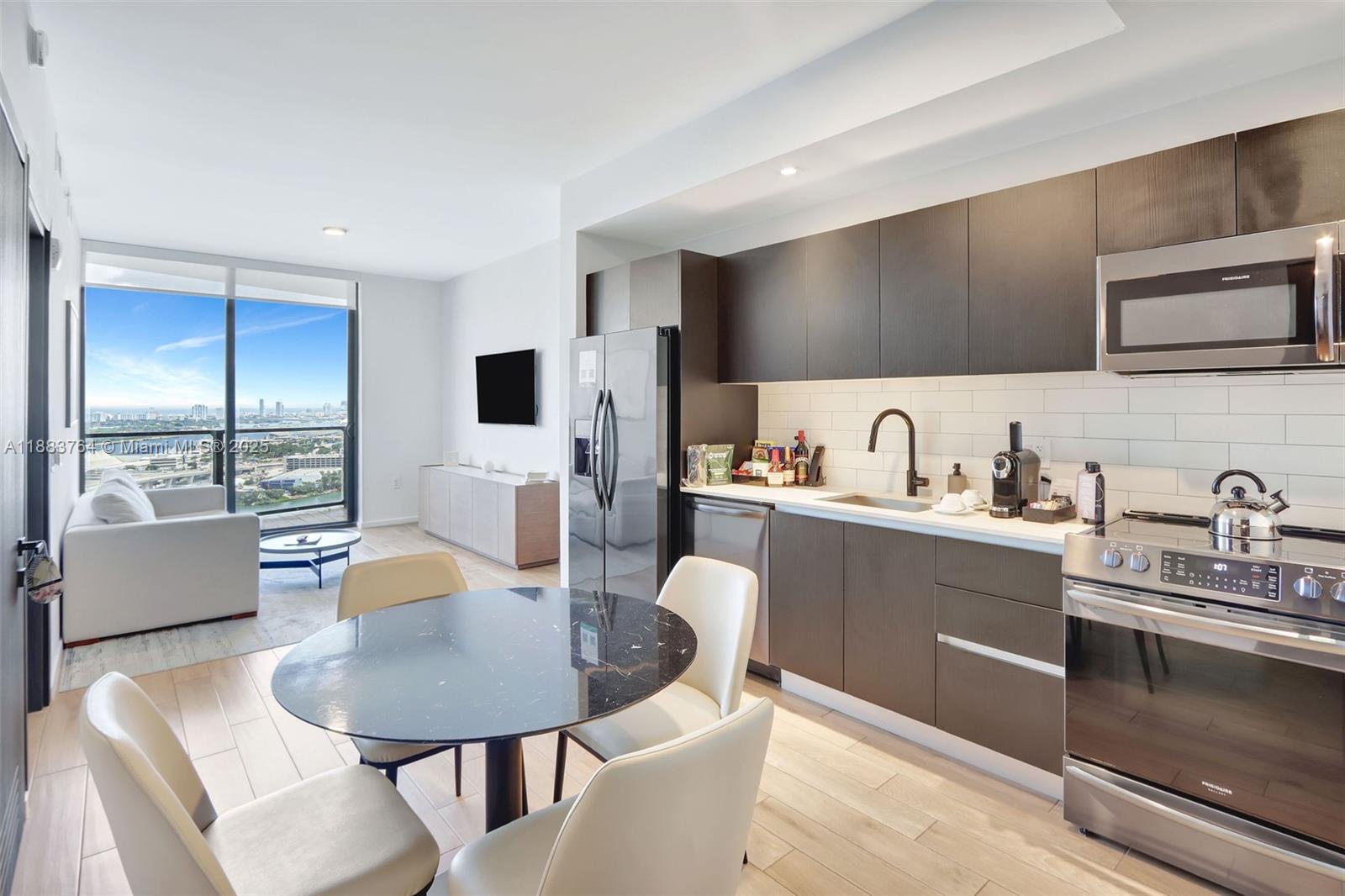 A modern kitchen and dining area feature dark cabinetry, stainless steel appliances, and city views — 398 NE 5th St # 2410, Miami FL 33132, MIAMI, FL