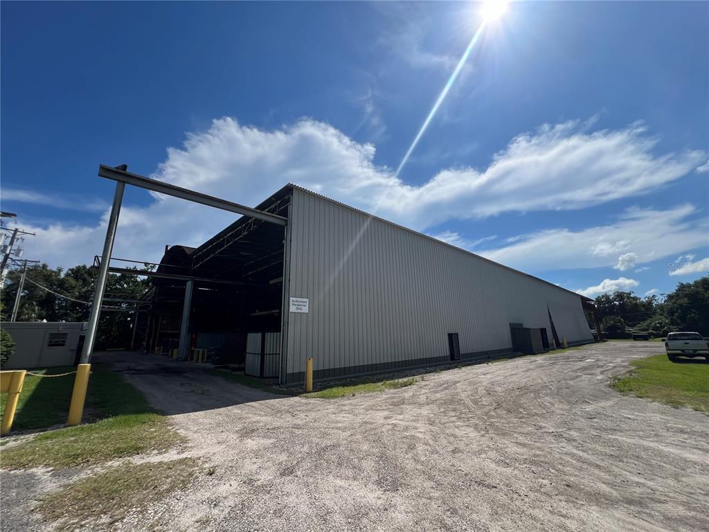 A large metal warehouse building stands on a dirt lot under a sunny sky — 5101 24TH AVENUE S, TAMPA, FL