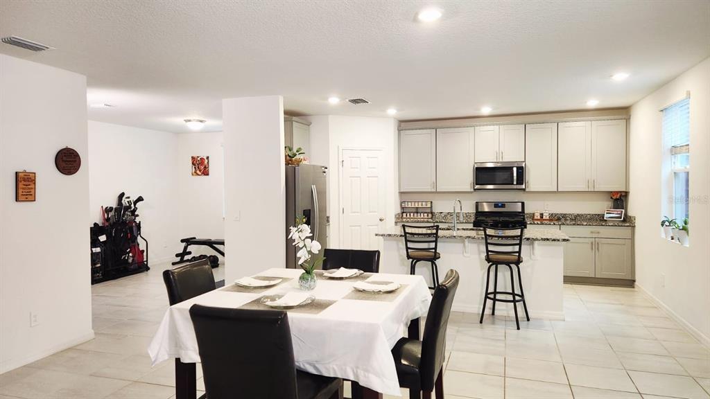 A kitchen with light cabinets and granite countertops overlooks a dining area and living space — 5190 MINNEOLA LANE, ST CLOUD, FL