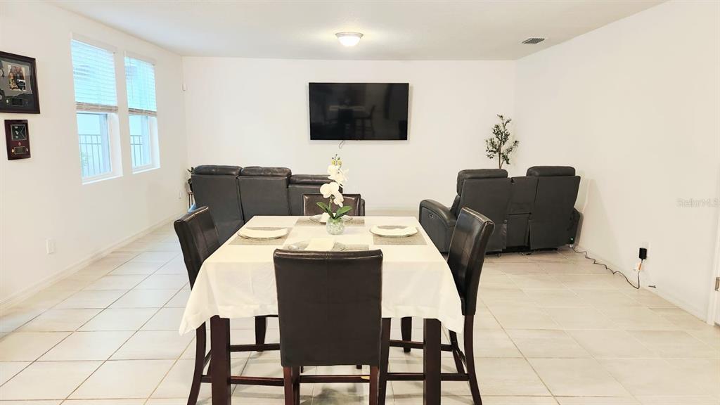 A dining area with a table and chairs sits in front of a living room — 5190 MINNEOLA LANE, ST CLOUD, FL