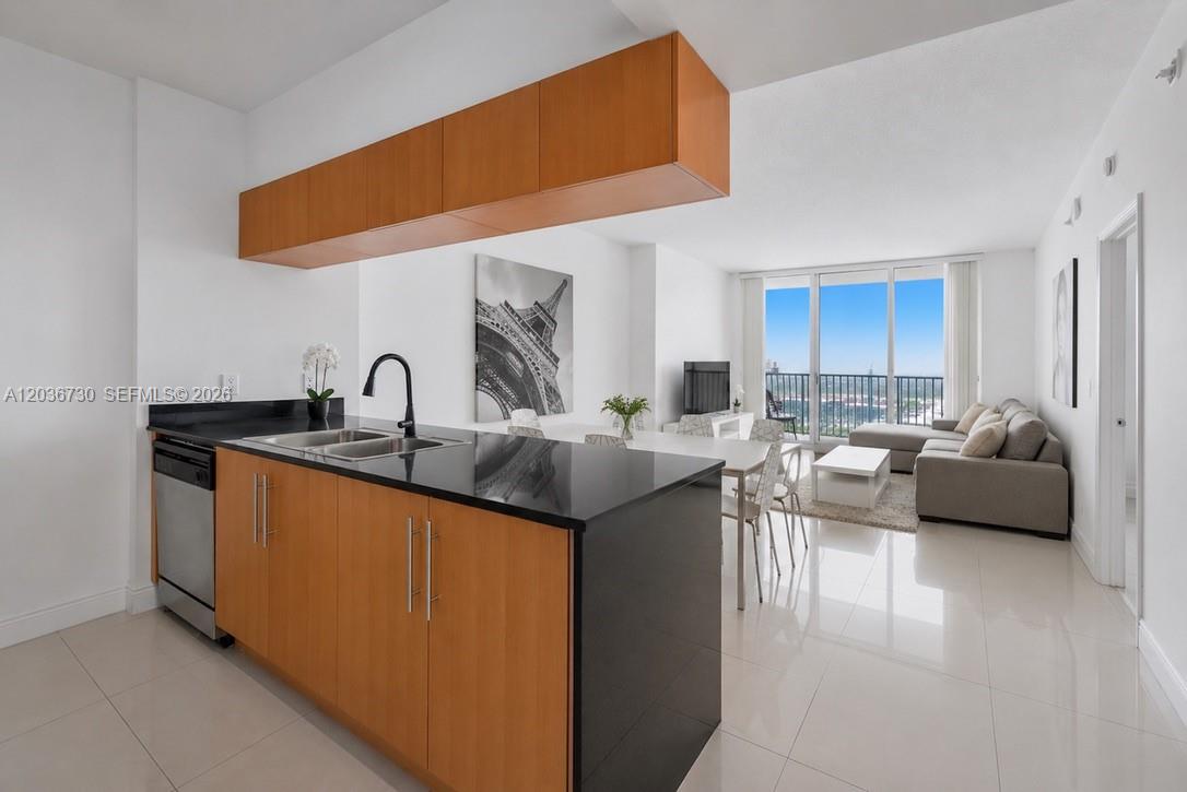 A modern kitchen with wood cabinets and black countertops overlooks an open-concept living area — 1750 N Bayshore Dr # 3811, Miami FL 33132, MIAMI, FL