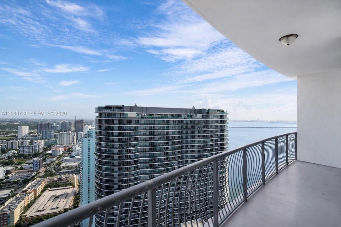 A high-rise balcony overlooks a large residential tower and a body of water — 1750 N Bayshore Dr # 3811, Miami FL 33132, MIAMI, FL