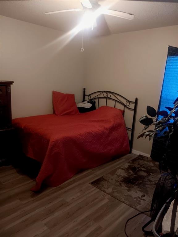 A bedroom features a bed with a red quilt, a ceiling fan, and wood-look flooring — 16705 SW 22ND TERRACE ROAD, OCALA, FL