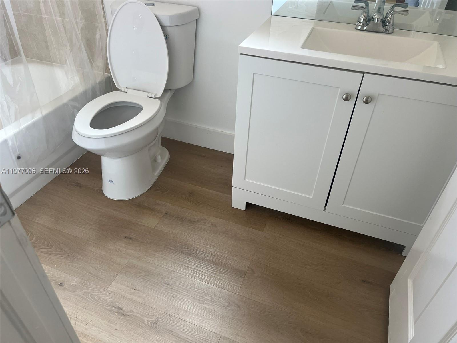 A bathroom features a white vanity, a toilet, and light wood-look flooring — 2511 NE 41st Ter, Homestead FL 33033, HOMESTEAD, FL