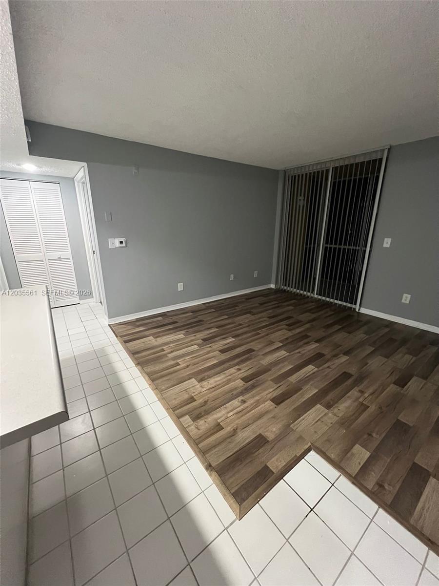 An interior view shows a room with wood-look flooring, white tile, and a sliding glass door — 3985 W Mcnab Rd # A103, Pompano Beach FL 33069, POMPANO BEACH, FL