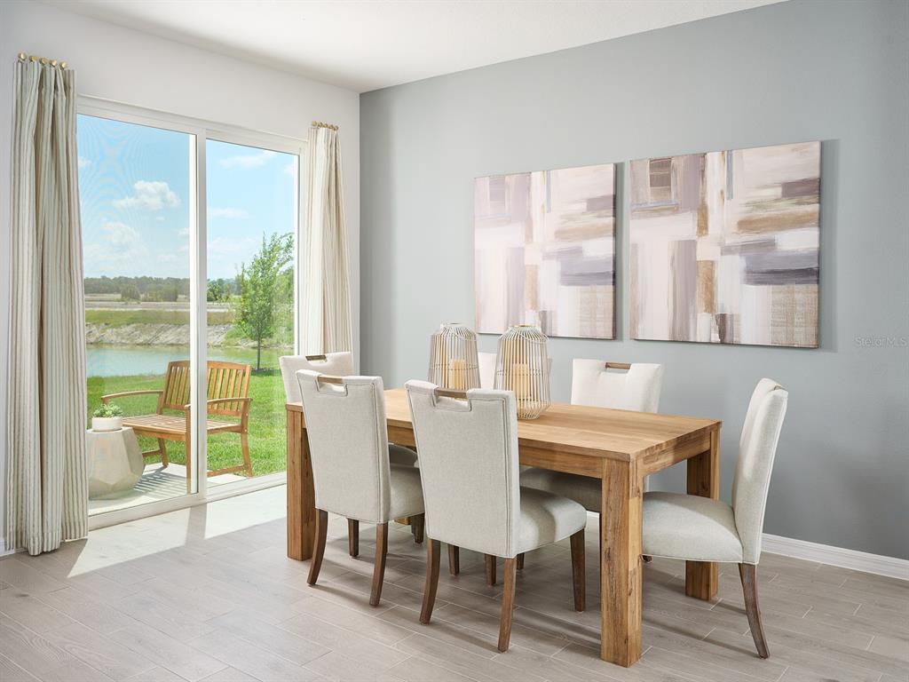 A dining room with a wooden table, upholstered chairs, wall art, and a sliding glass door — 14123 HARVEST PINES LANE, HUDSON, FL