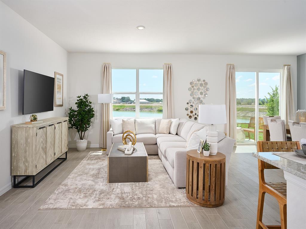 A living room features a sectional sofa, a television console, and a view of water — 14123 HARVEST PINES LANE, HUDSON, FL