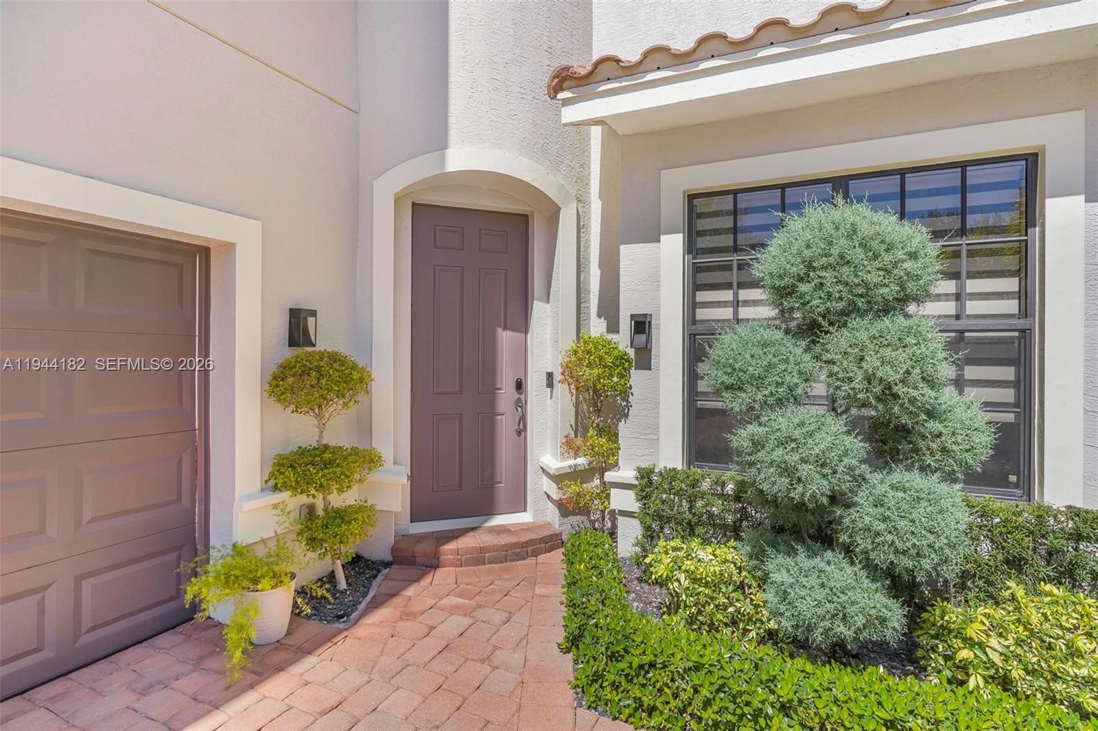 A brick walkway leads to a front door next to a garage and landscaping — 10185 Cameilla St, Parkland FL 33076, PARKLAND, FL