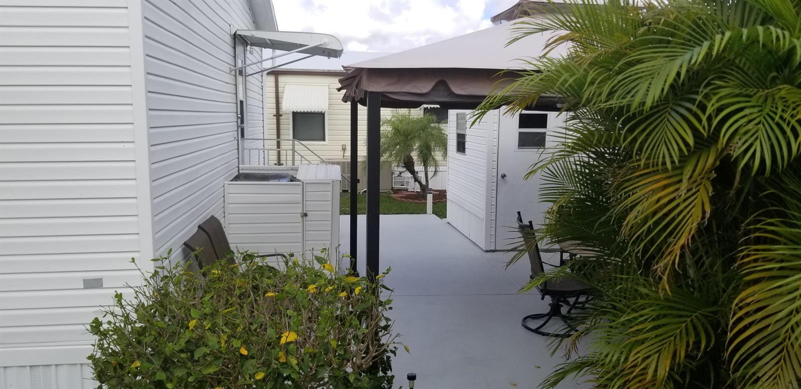 A patio area features a gazebo, outdoor furniture, and a storage unit between two homes — 14578 Glenview Drive, Delray Beach FL 33445, DELRAY BEACH, FL