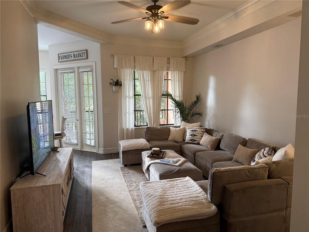 A living room features a large sectional sofa, a television, and French doors — 513 MIRASOL CIRCLE UNIT 203, CELEBRATION, FL