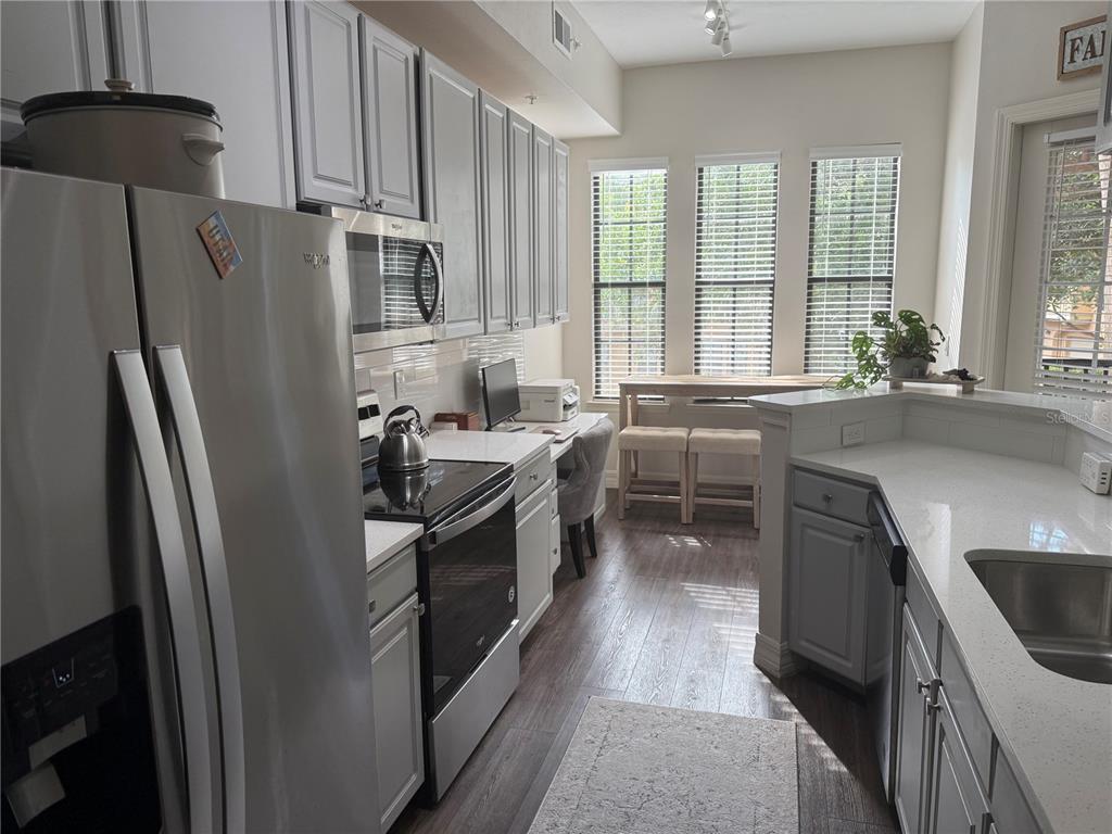 A kitchen features stainless steel appliances, light gray cabinets, white countertops, and a dining area — 513 MIRASOL CIRCLE UNIT 203, CELEBRATION, FL