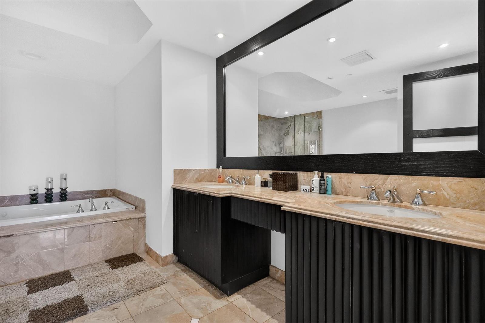 A bathroom features a double vanity with marble countertops, black cabinetry, and a soaking tub — 9595 Collins Avenue # 8f, Surfside FL 33154, SURFSIDE, FL