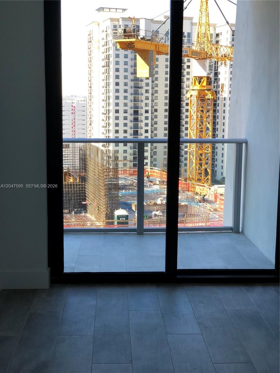 A view of a construction site with a yellow crane from a tiled balcony — 1010 Brickell Ave # 3709, Miami FL 33131, MIAMI, FL