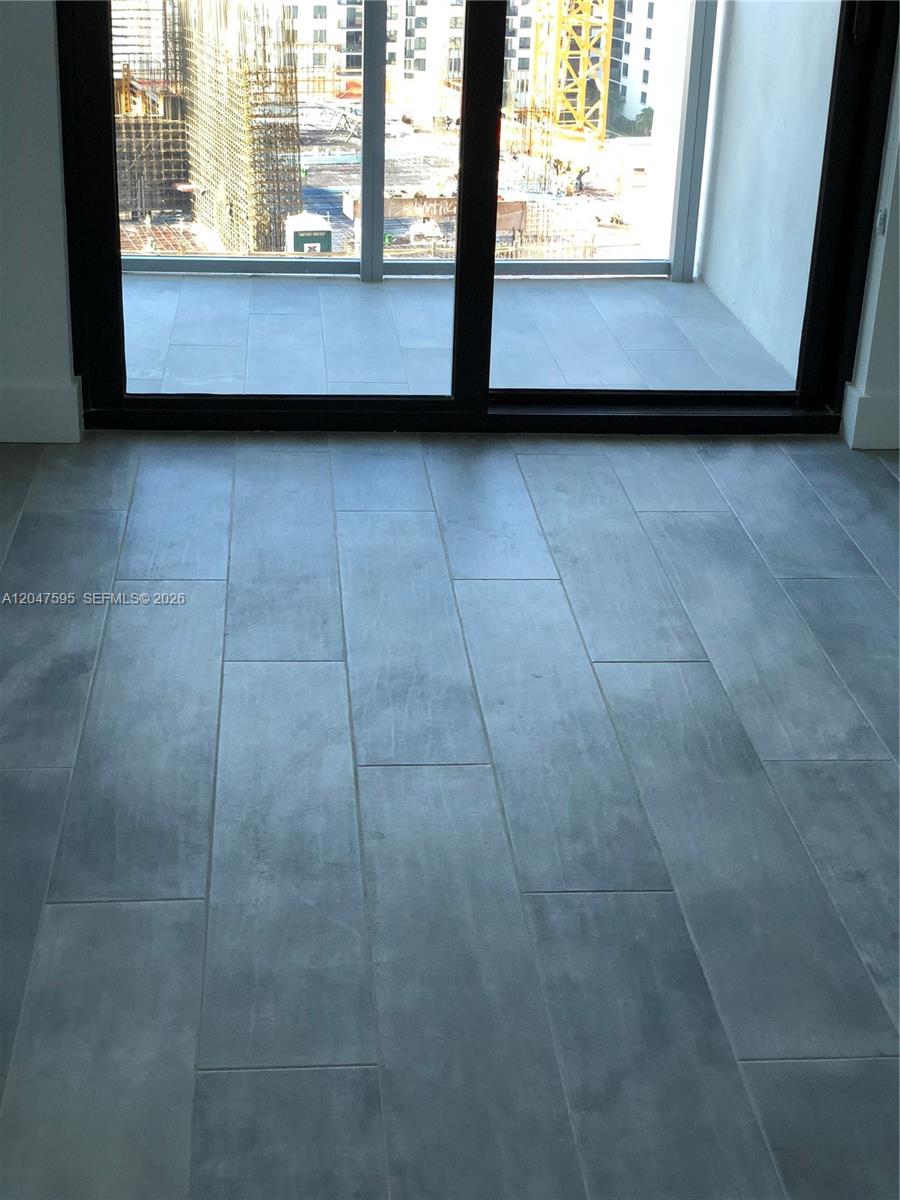A room with gray tile flooring features a large sliding glass door overlooking a construction site — 1010 Brickell Ave # 3709, Miami FL 33131, MIAMI, FL