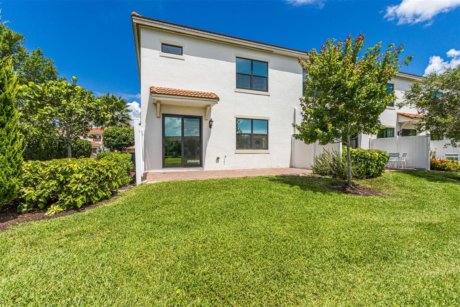 The exterior of a two-story white stucco house features a patio and a grassy backyard — 10124 Brickhill Drive # 10124, Boca Raton FL 33428, BOCA RATON, FL