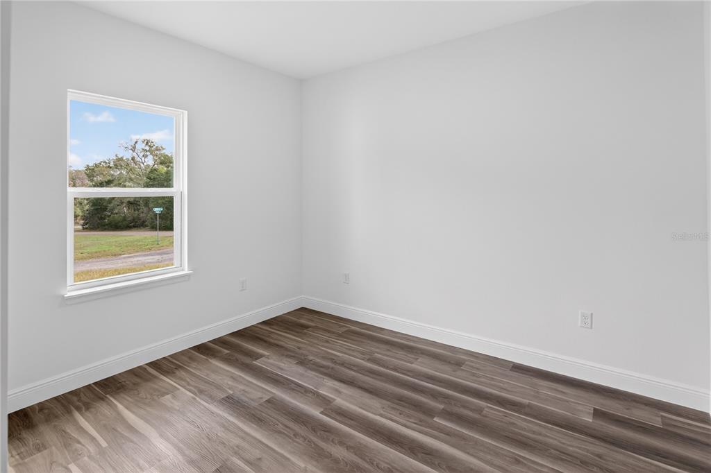 An empty bedroom features white walls, wood-look flooring, and a single window — 9066 N AKOLA WAY, CITRUS SPRINGS, FL