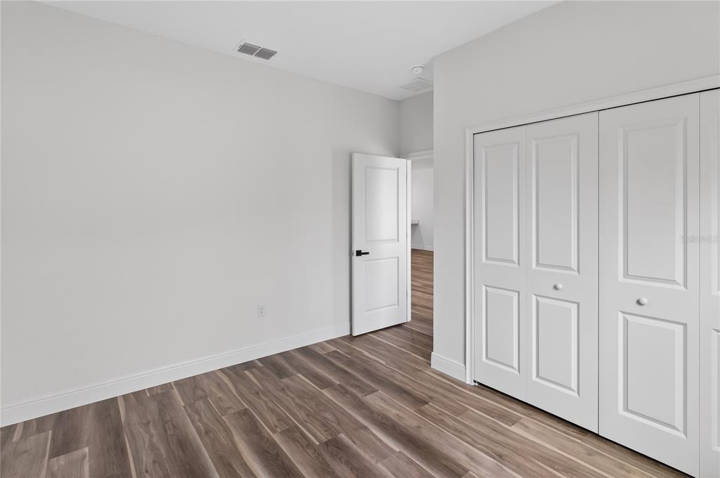 An empty bedroom features light gray walls, wood-look flooring, and white paneled closet doors — 9066 N AKOLA WAY, CITRUS SPRINGS, FL