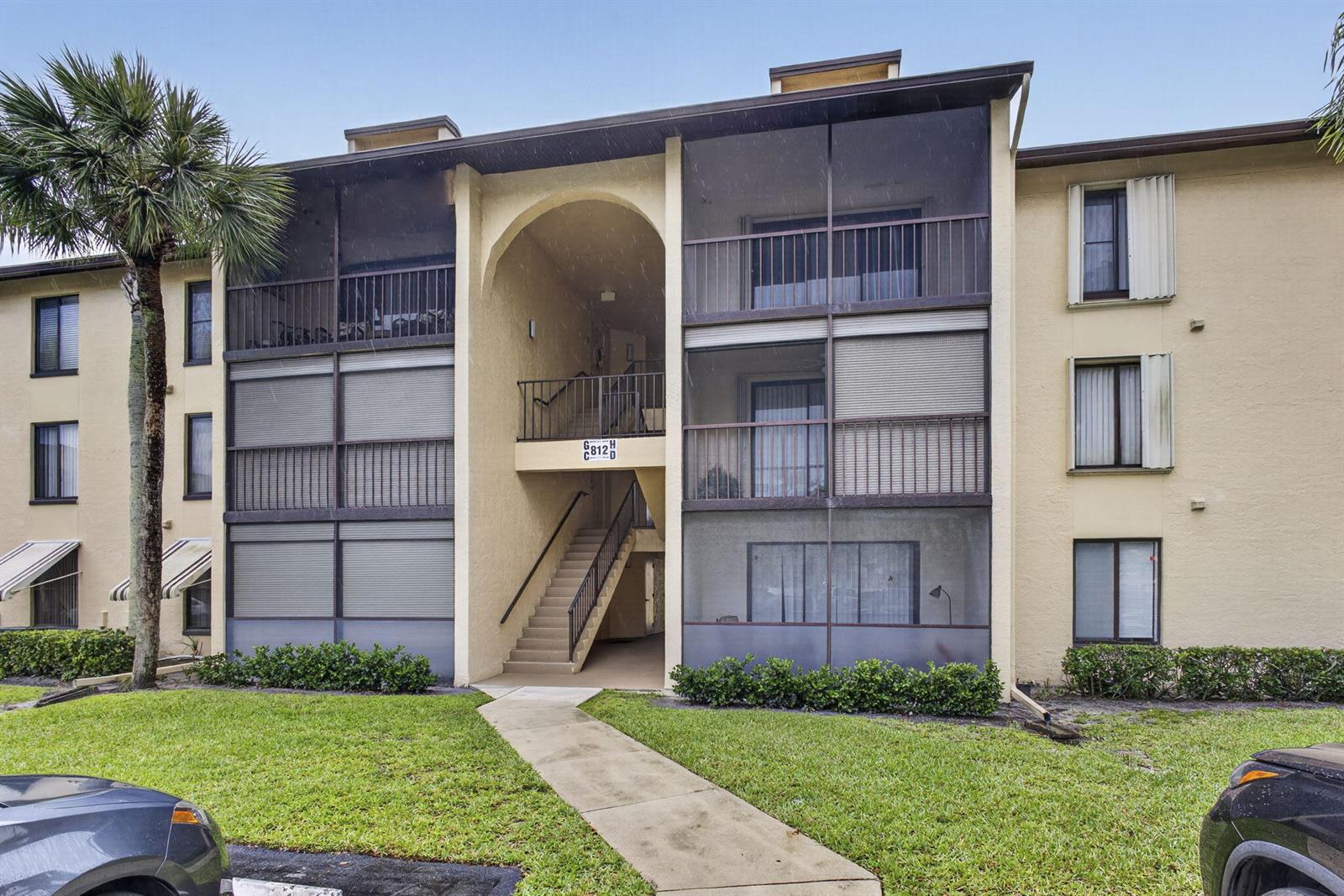 A three-story apartment building features screened balconies, a central staircase, and a concrete walkway — 812 Sky Pine Way # G1, FL 33415, FL