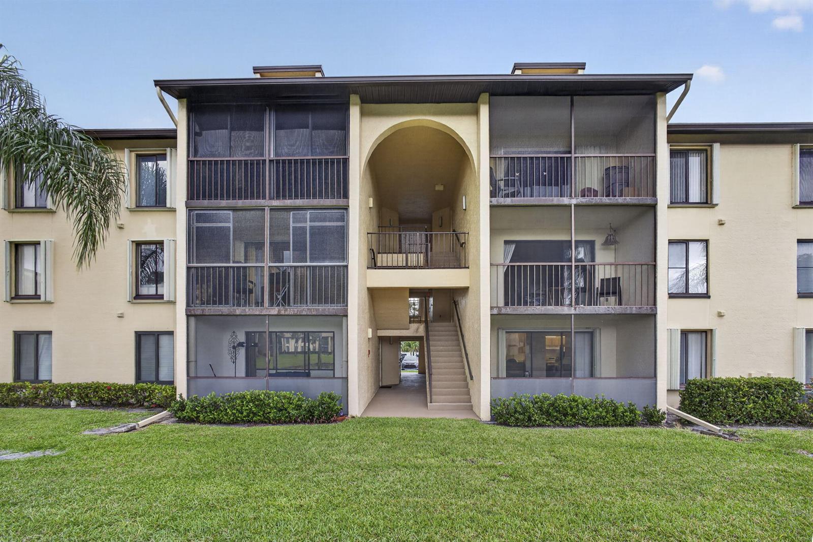 A three-story apartment building features screened balconies, an arched entryway, and an outdoor staircase — 812 Sky Pine Way # G1, FL 33415, FL