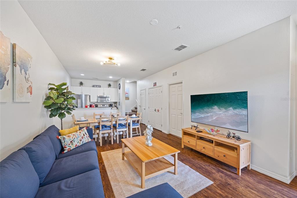 A living room and dining area with a blue sofa, wood coffee table, and television — 8945 SHINE DRIVE, KISSIMMEE, FL