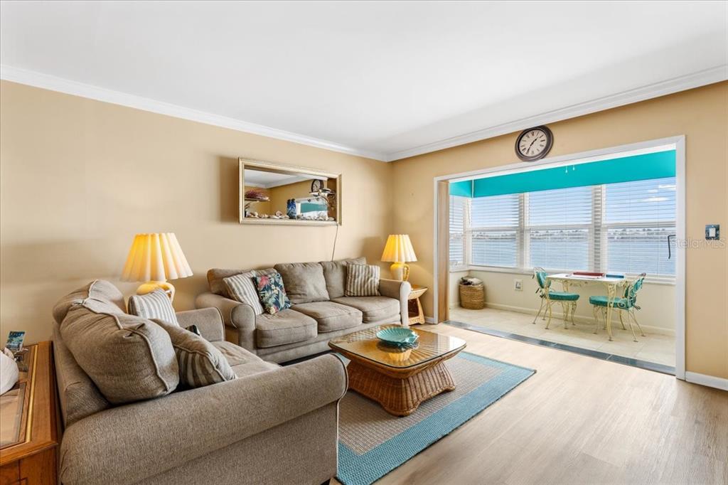 A living room with beige walls, two sofas, a coffee table, and a sunroom with water views — 5020 BRITTANY DRIVE S UNIT 118, ST PETERSBURG, FL