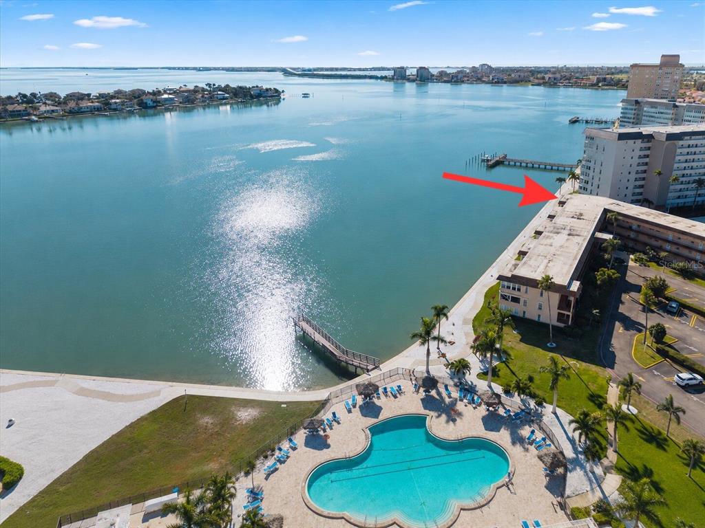 An aerial view shows a waterfront condominium complex with a swimming pool and a pier — 5020 BRITTANY DRIVE S UNIT 118, ST PETERSBURG, FL